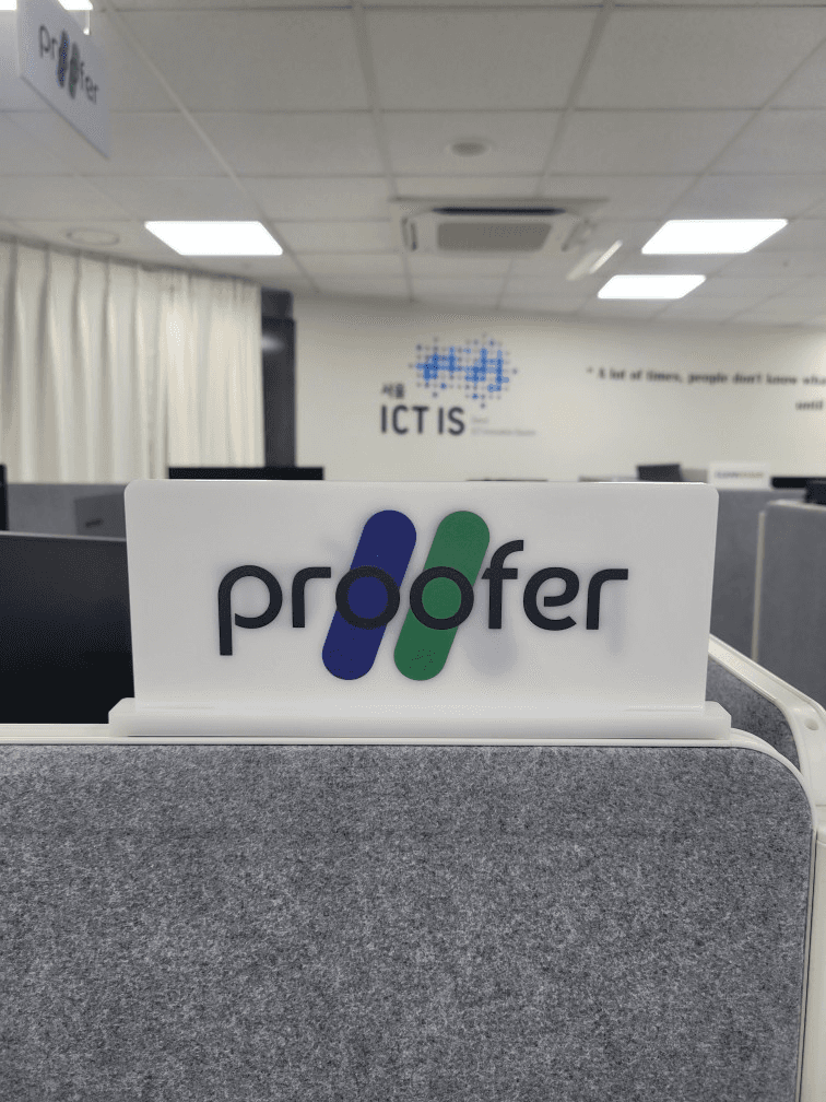 사무실 파티션 위에 세운 proofer 아크릴 명패와 뒤쪽 벽의 ICT IS 로고