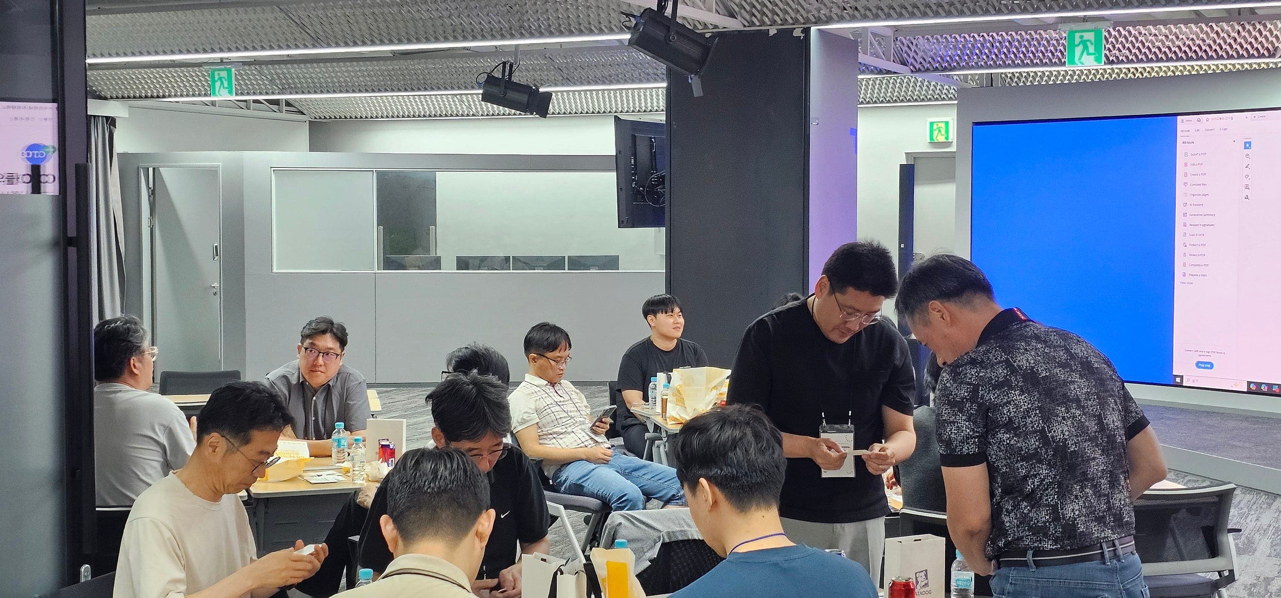 테이블 사이에 선 두 참여자가 명함을 들여다보며 인사하는 자율 네트워킹 장면