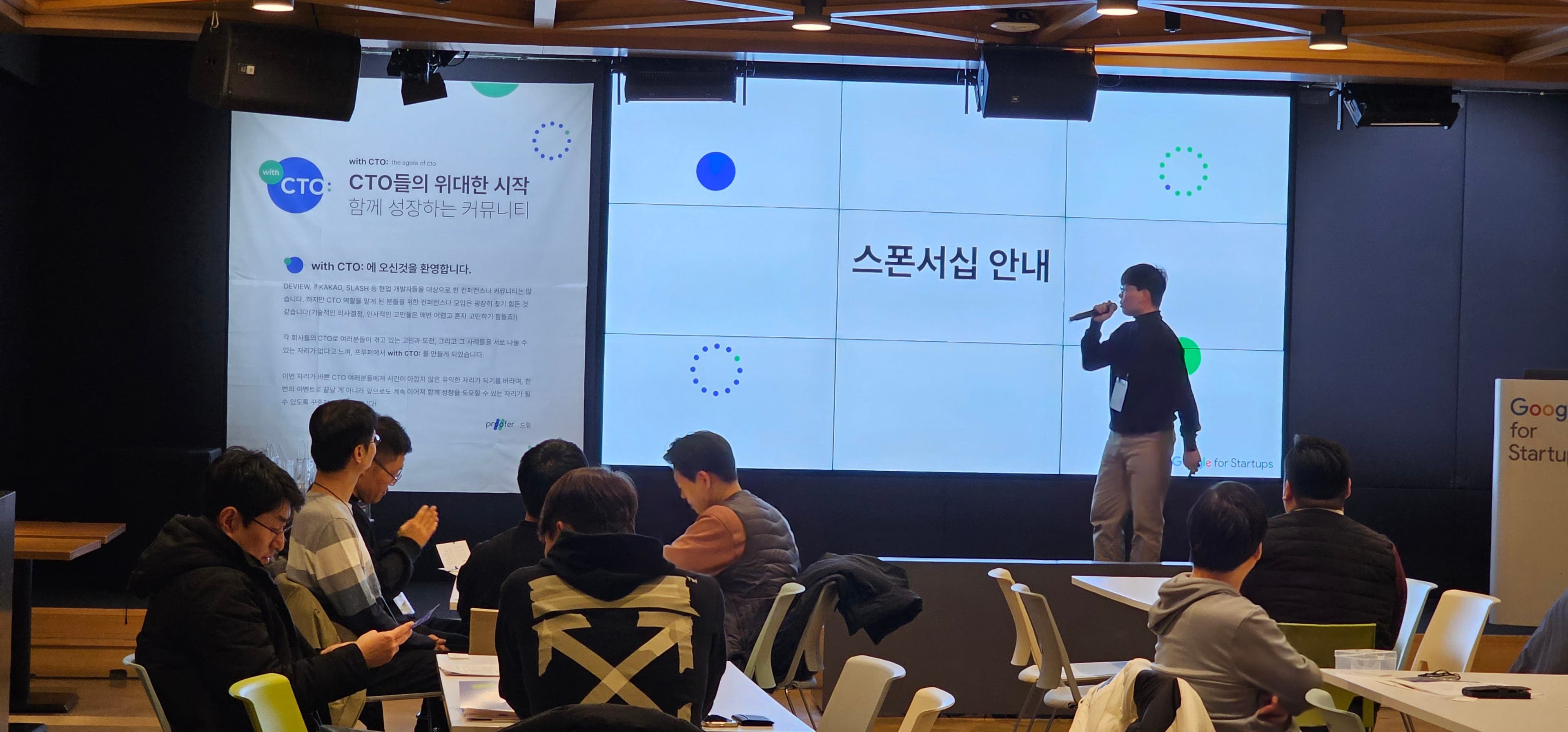 스폰서십 안내 슬라이드 앞에서 발표자가 마이크를 들고 설명하는 장면