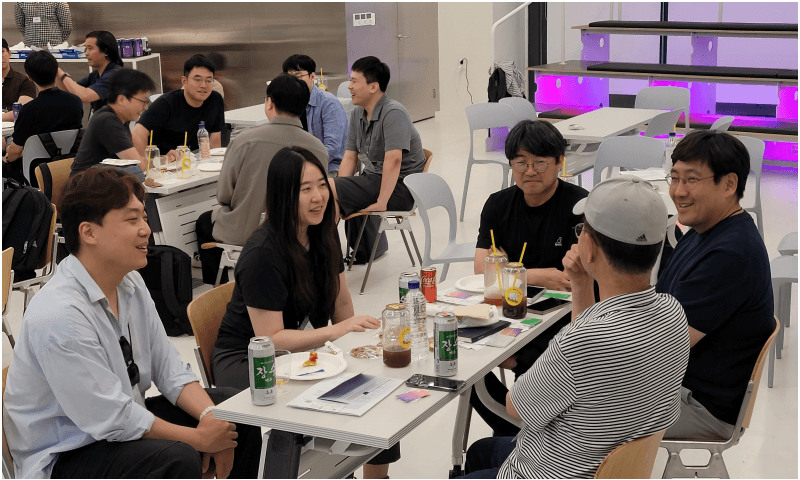 캔음료를 앞에 두고 테이블에 둘러앉아 웃으며 대화하는 참가자들
