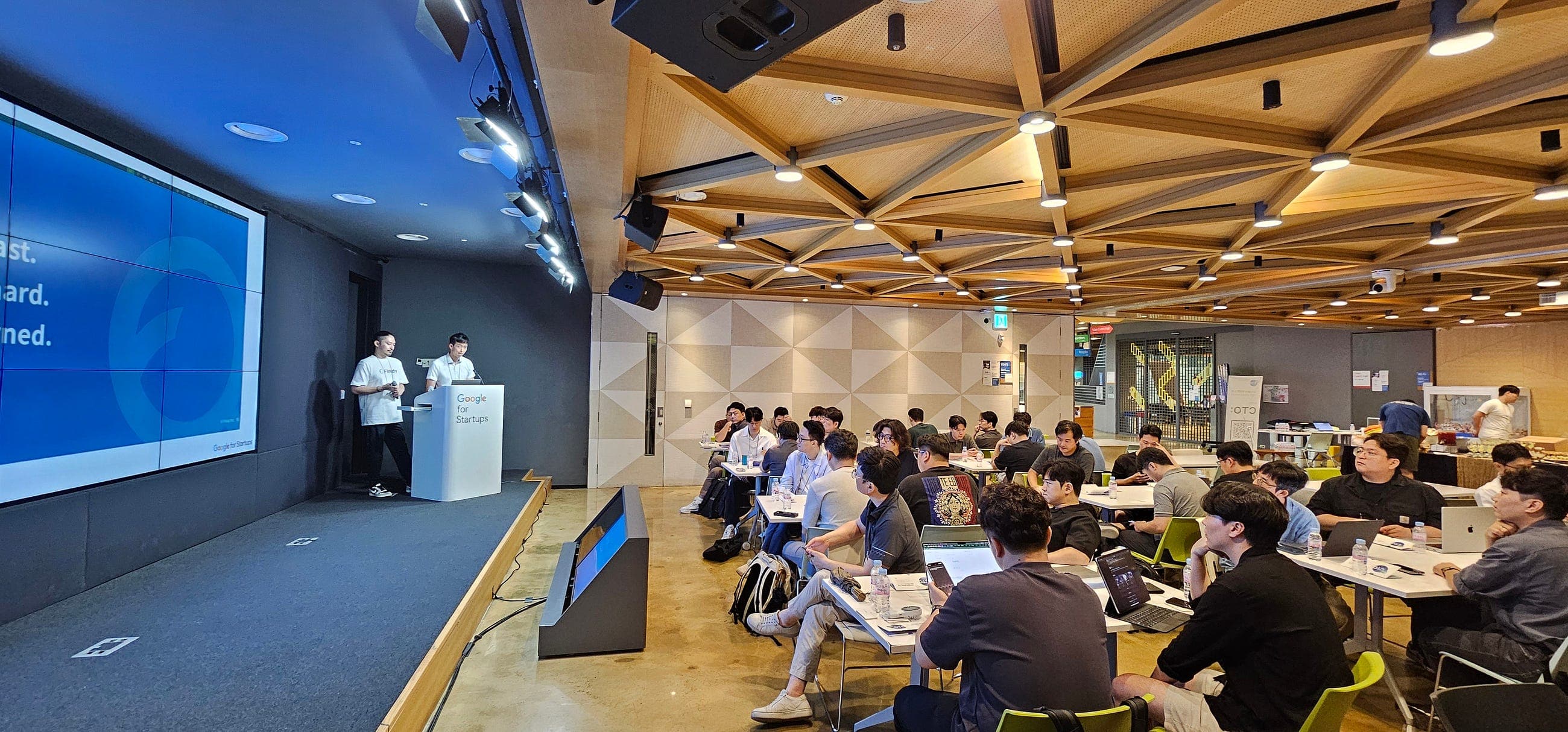 Google for Startups 연단에서 Findy 팀 두 연사가 발표하고 참여자들이 테이블에서 듣는 장면