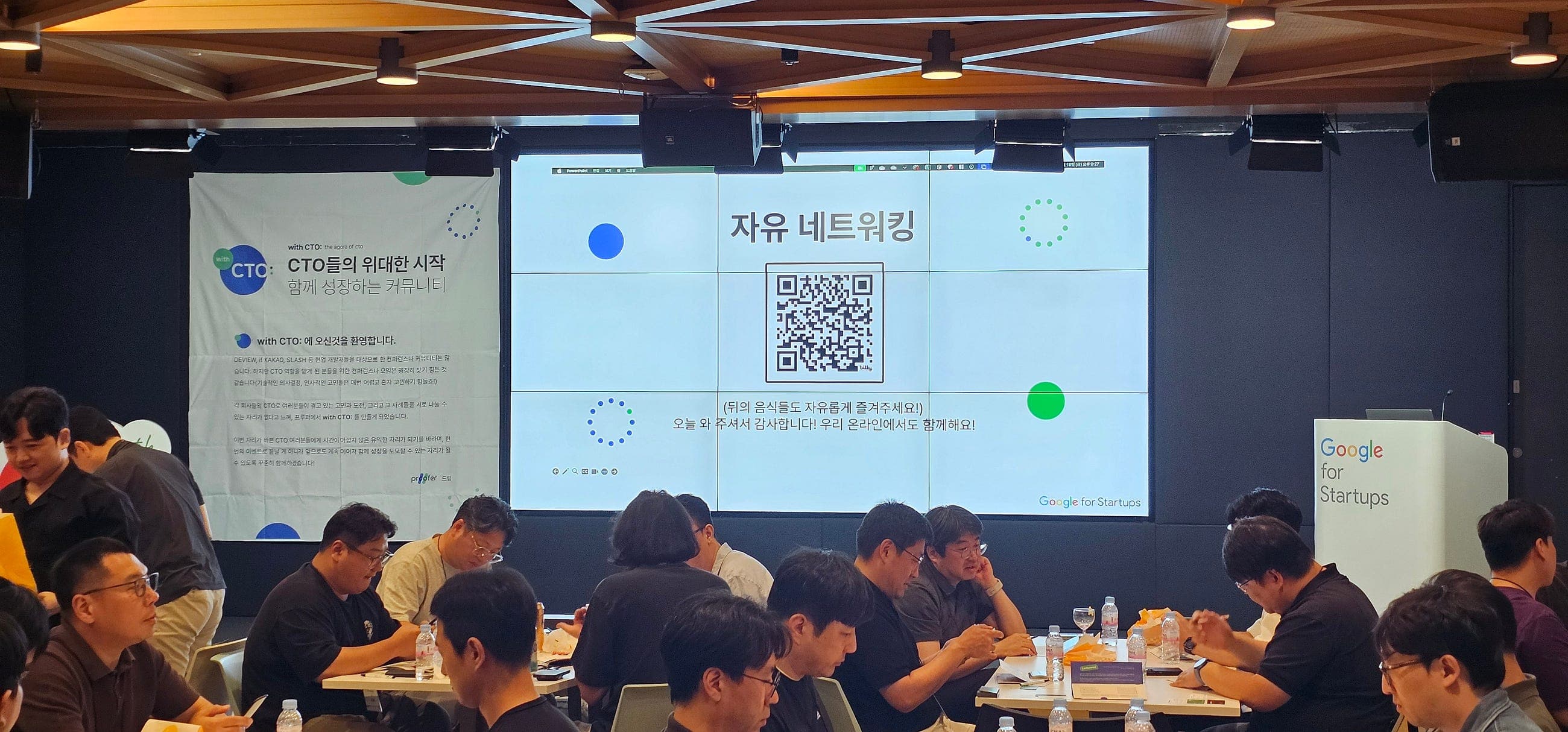 자유 네트워킹 글자와 QR 코드를 띄운 화면 아래 테이블에 둘러앉은 참여자들