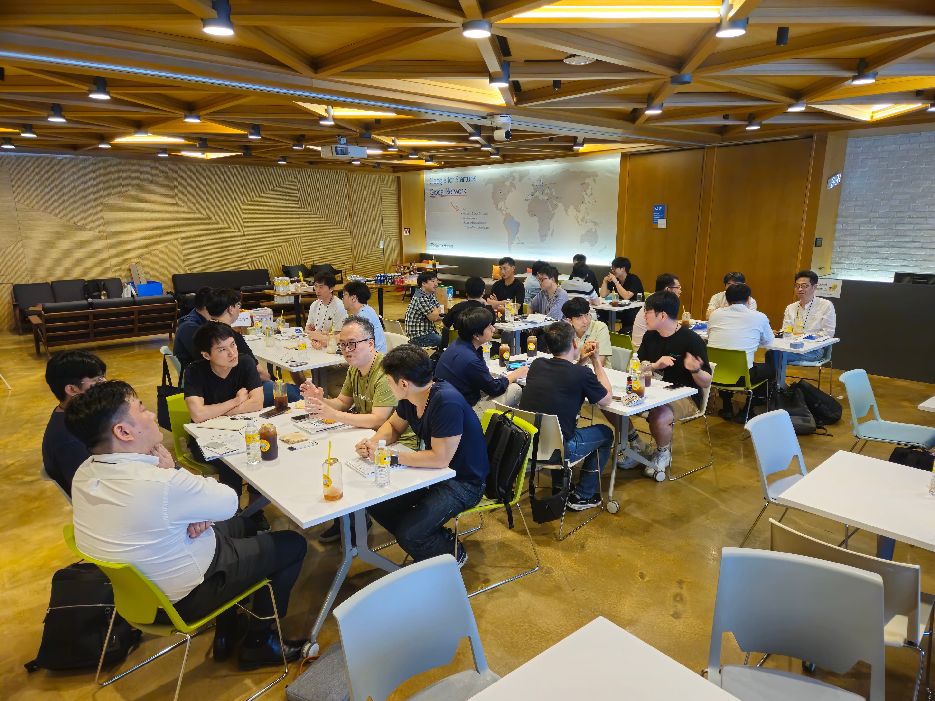 Google for Startups Global Network 지도 벽 앞 테이블에서 대화하는 참가자들